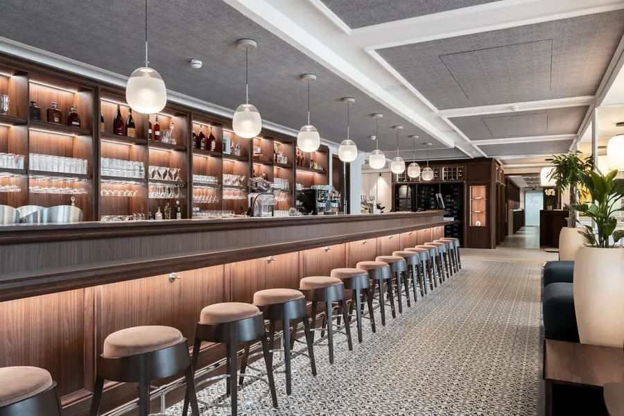 Le bar mêle boiseries chaleureuses, éclairages tamisés et détails contemporains dans un esprit de maison de bord de mer.