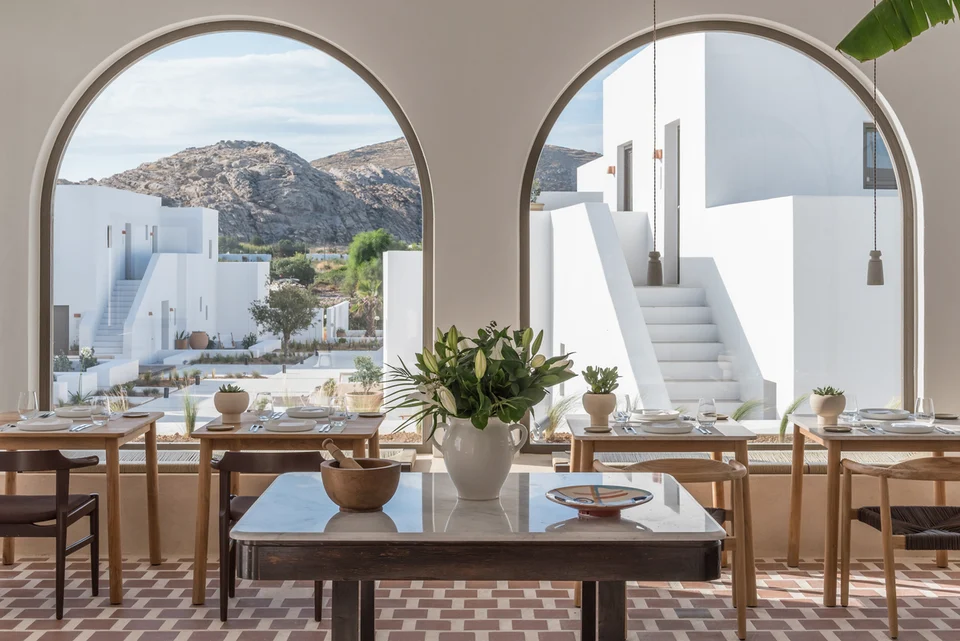 Au restaurant Mr E, les grandes arches cadrent les bâtiments blancs de l’hôtel et renforcent la continuité entre intérieur et extérieur.